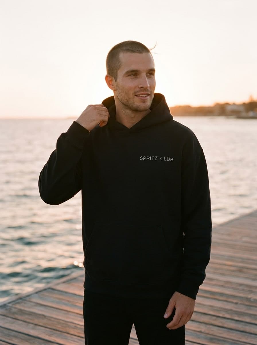 The hoodie on a man on a jetty by the sea at golden hour